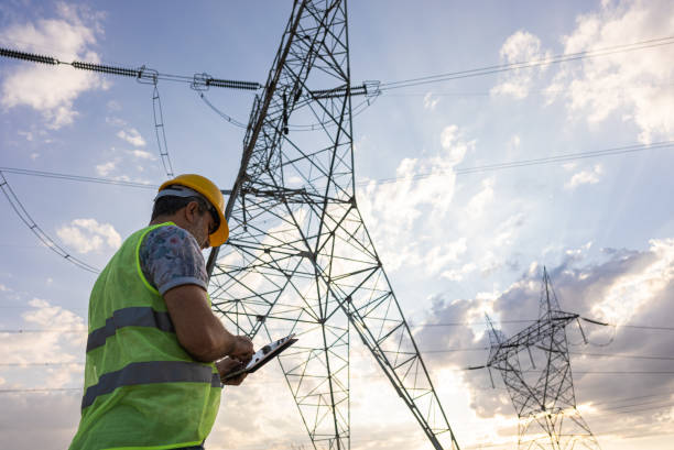 ingenieros frente a la planta de energía usando una tableta digital - torre de conducción eléctrica fotografías e imágenes de stock