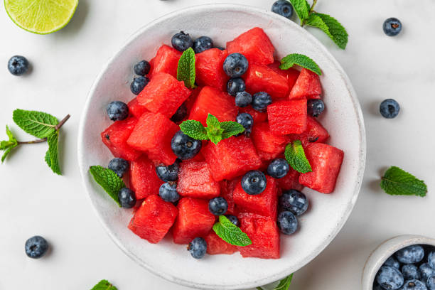 istock Watermelon and blueberry fruit summer salad with lime juice and mint on white marble table. top view 1334339211