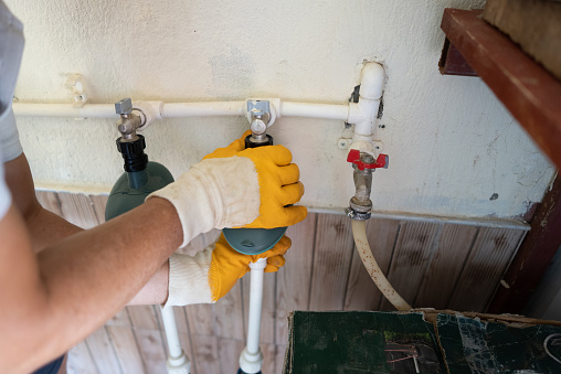 Males plumber in rubber gloves connect thick long pipes for automatic irrigation.