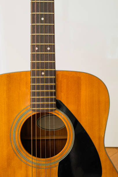 istock Yellow guitar, partial view, upright position on white wall and maple floor background 1334343245