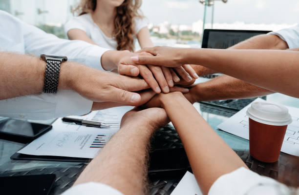 group of young business people putting their palms together stock photo
