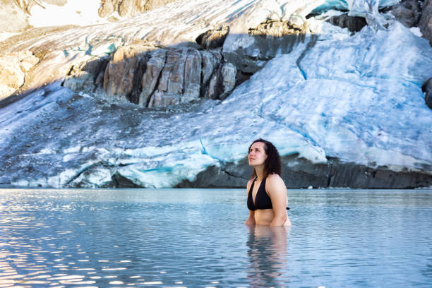 Adventurous White Caucasian Adult Woman Swimming in Ice Cold Glacier Lake Adventurous White Caucasian Adult Woman Swimming in Ice Cold Glacier Lake on top of a Mountain. Wedgemount, Whistler, British Columbia, Canada. woman cold water swimming stock pictures, royalty-free photos & images