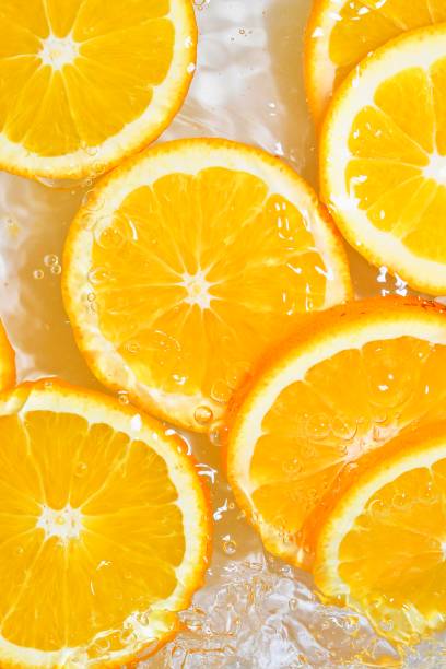 Close up view of the orange slices for lemonade background. Texture of cooling sweet summer's drink with macro bubbles on the glass wall. Flat design stock photo