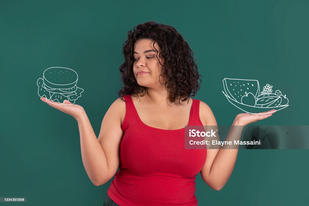 woman choosing between hamburger and salad young woman with curly hair showing a salad and a hamburger illustration with a doubt expression Uncertainty Stock Photo