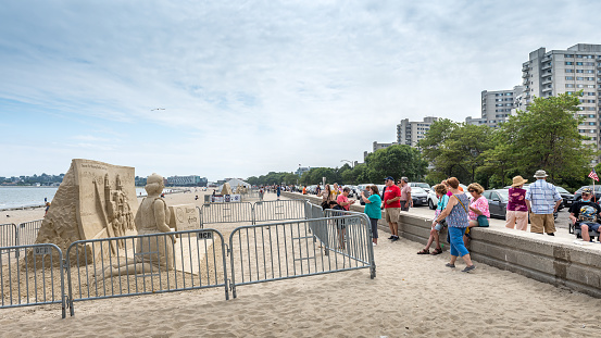 Revere, MA, USA - August 9, 2021: Tourist enjoying the annual sand sculpture contest at Revere Beach. This is a public beach in Revere, Massachusetts, located about 5 miles away. north of downtown Boston. This beach became the first public beach in the United States in 1896. It is easily accessible by the MBTA Blue Line from Boston, and can accommodate up to one million visitors in one weekend during its annual sand sculpture competition.
