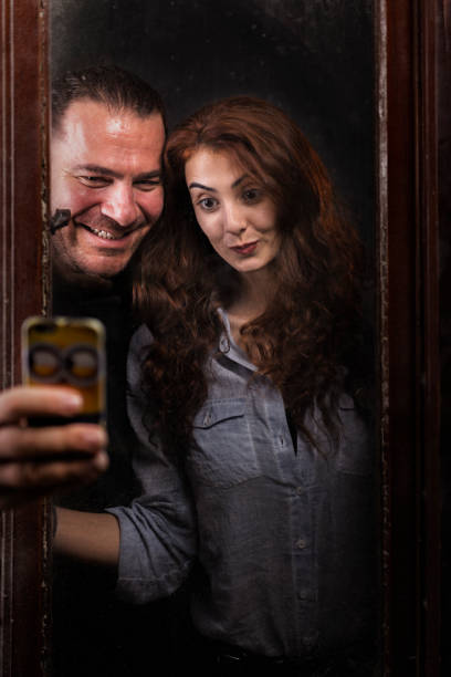 un homme d’âge moyen et une jeune fille s’amusent à prendre une photo de selfie derrière la fenêtre du studio. - smoking women smoking issues mature adult photos et images de collection