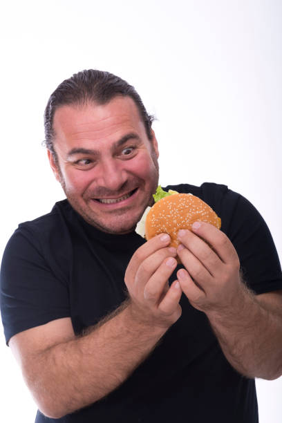istock Middle aged man overweight man staring at hamburger and is ready to eat it. 1334354322