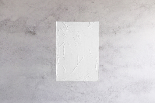 Blank white wheatpaste glued paper poster mockup on concrete wall background