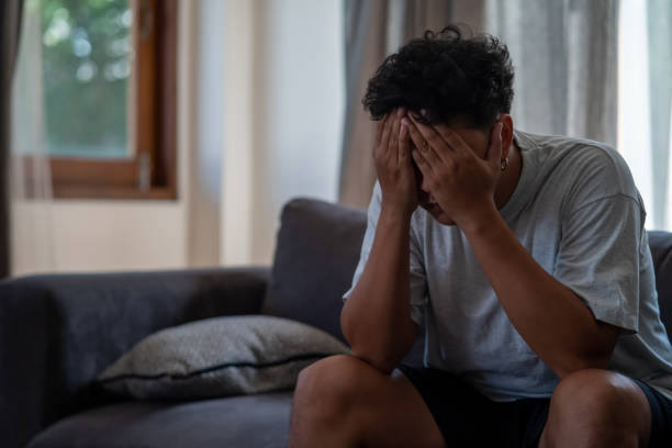 istock Depressed Asian man sitting on sofa in living room 1334359467