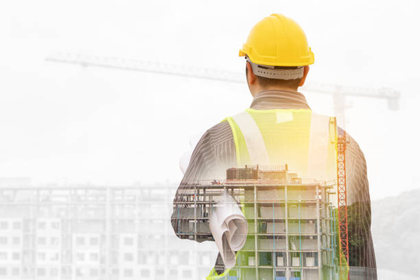 istock Double exposure image of professional engineer in protective helmet and blueprints paper at building construction site 1334359749