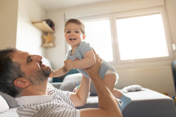 istock Cheerful father and baby boy having fun at home 1334359927