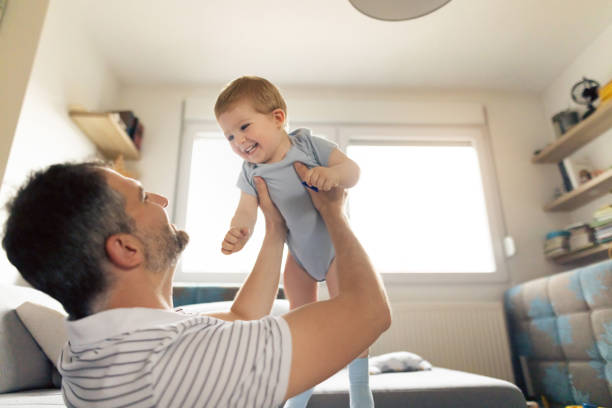 istock Smiling father and baby boy having fun at home 1334360493