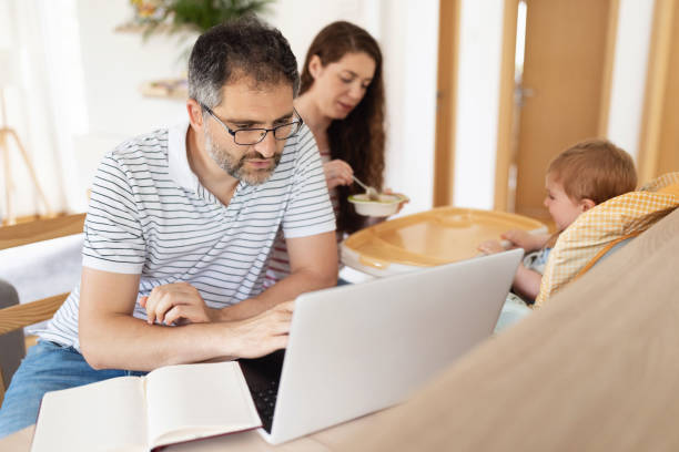 istock Caucasian man working while his wife feeding their baby boy 1334361041