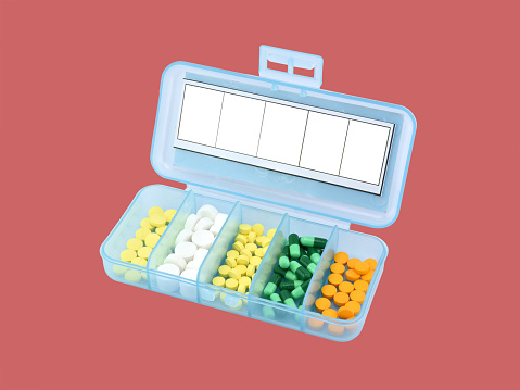 blue translucent plastic box divided into compartments with label stickers for organize daily medications