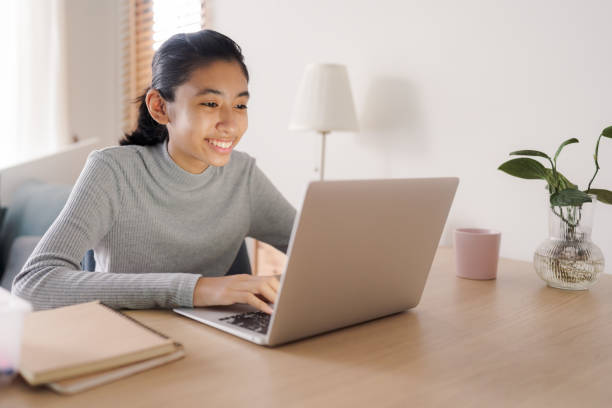 istock Asian woman using laptop at home 1334390875