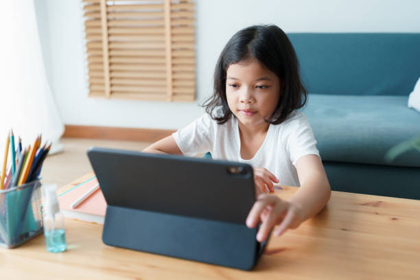 istock asian little girl using tablet digital at home 1334391476