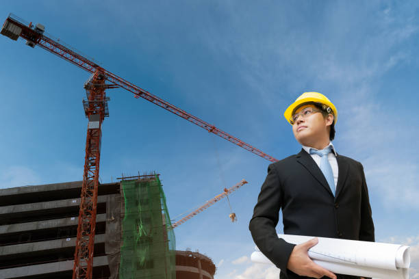 istock Engineer holding blueprint in his hand in construction site with crane machine  background 1334392621