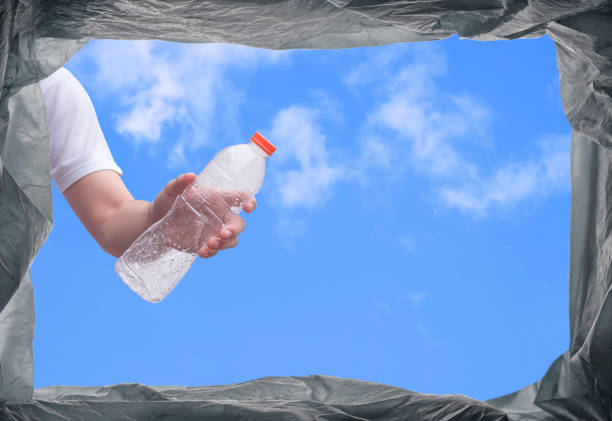young man hand throwing plastic water bottle into trash bin in public area
