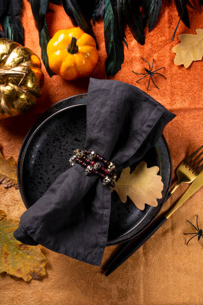 istock Halloween table setting concept. Plate, golden cutlery, pumpkins, spooky Halloween decorations and autumn leaves on the table vertical photo 1334397721