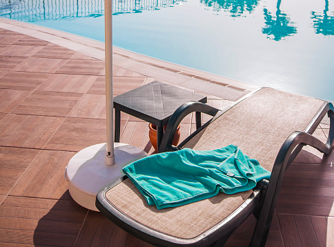 Sun-lounger and towel near the pool. Background for concept summer vacation