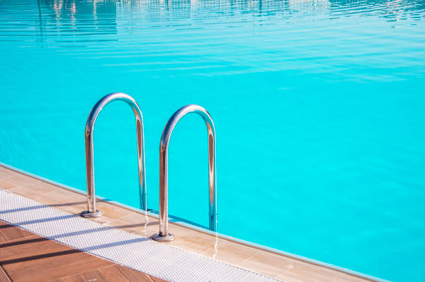 istock Swimming pool with turquoise water. Metal pool ladder casts a shadow 1334398120