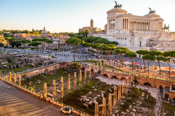 the warm light of the sunset illuminates the trajan's forum in rome with the altare della patria in the background - het forum van rome stockfoto's en -beelden