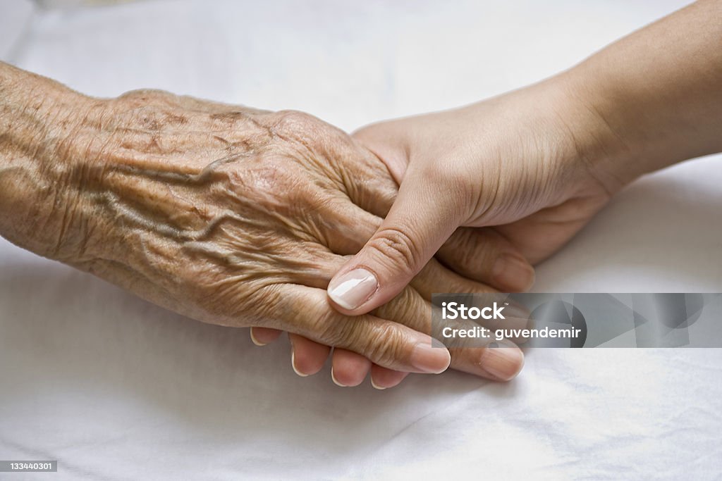 Mano de mujer joven sosteniendo la mano de un senior - Foto de stock de Tercera edad libre de derechos