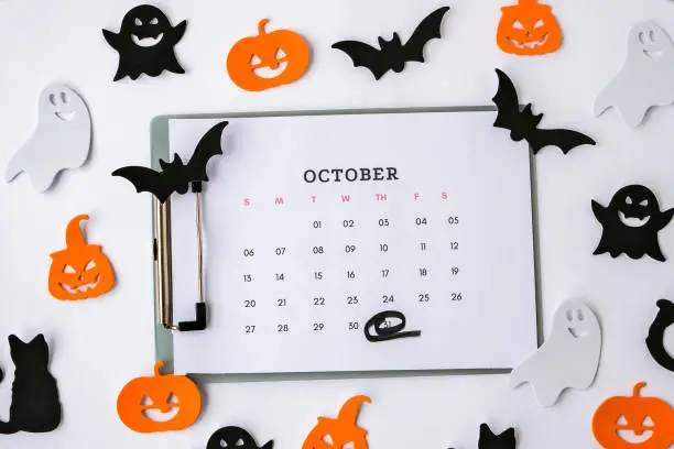 Photo of Calendar 31st of October date. Halloween background. Planning party. Flat lay. Top view. Halloween bat, pumpkin ghost decorations