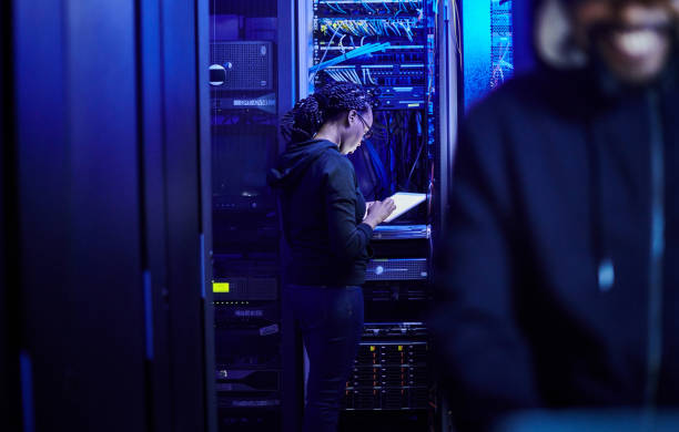 istock Shot of a young male computer programer using a laptop while standing in a dark server room 1334405439