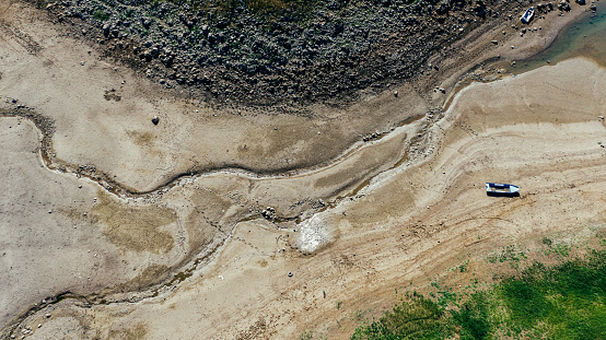 Extreme weather conditions making desert on the places where should be lake or river. Boat stay stranded deep on land. Climatic change impact. Aerial view