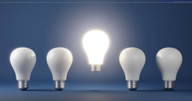 istock Glowing light bulb on bright between others on dark blue background 1334409810