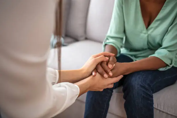 Photo of African psychologist hold hands of girl patient, close up.