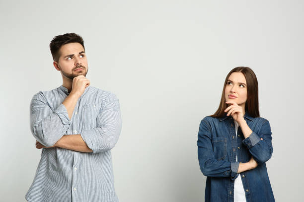 pensive couple on light background. thinking about answer for question - pensativo imagens e fotografias de stock