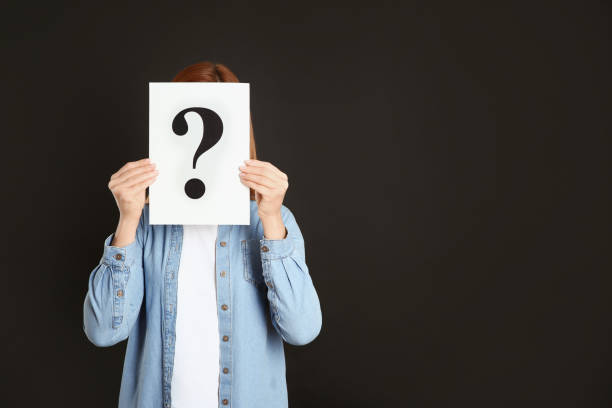istock Woman holding question mark sign on black background. Space for text 1334411617