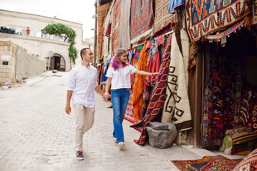 Couple in love buys a carpet and handmade textiles at an oriental market in Turkey. Hugs and cheerful happy faces of men and women