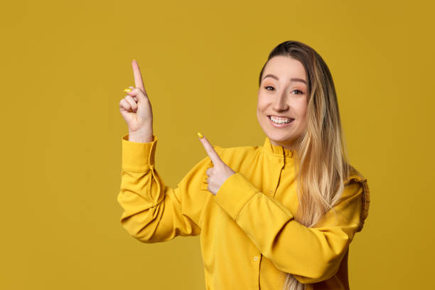 istock young woman pointing away on yellow background 1334417156