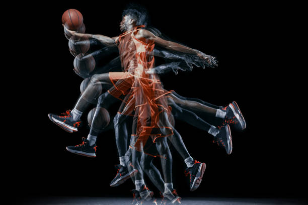 un joven africano, jugador de baloncesto en movimiento con el balón aislado sobre fondo negro. efecto estroboscópico - stroboscopic image fotografías e imágenes de stock