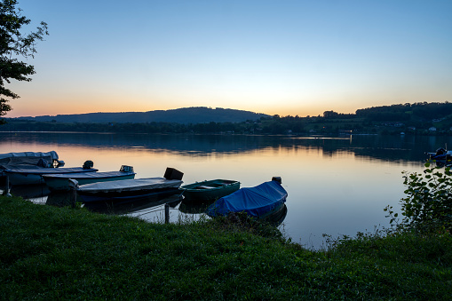 Sunset with boats moored at the shore of the lake