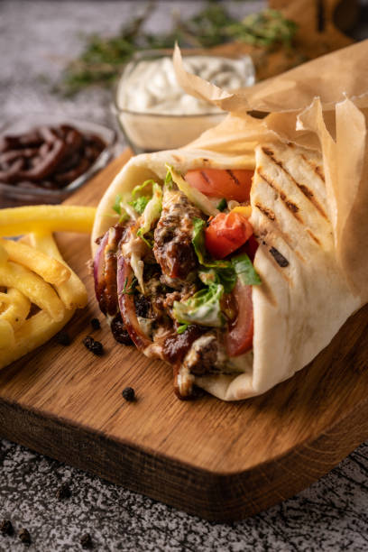 selective focus. doner kebab, a shawarma in a pit doner kebab, a shawarma in a pit of fresh vegetables and meat. with large spices. restaurant serving. on a dark background. for menus and ads shawarma stock pictures, royalty-free photos & images