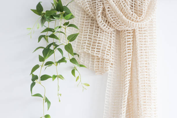 istock Green leaves with ivory fabric on a white wall. 1334420179