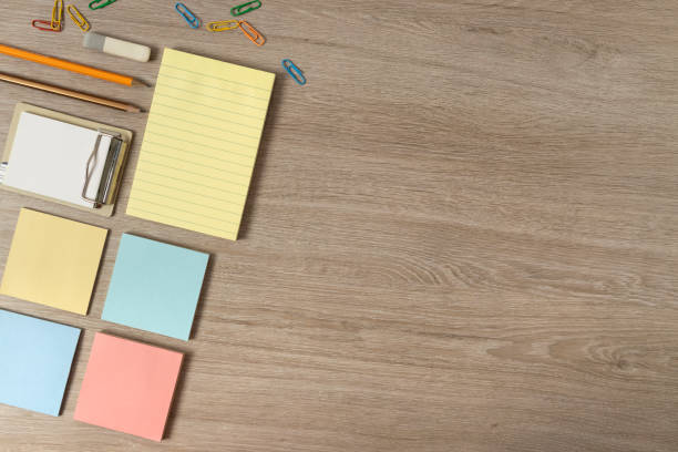 istock Top view of yellow,blue,pink note sheets,pencils and clips on the wooden table.Empty space 1334420199