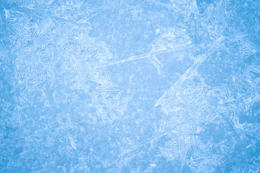 Openwork pattern of blue ice with a layer of white frost, snowflakes and natural illumination. Background.