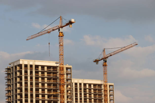 istock Construction cranes above unfinished residential buildings on cloudy sky background 1334421271