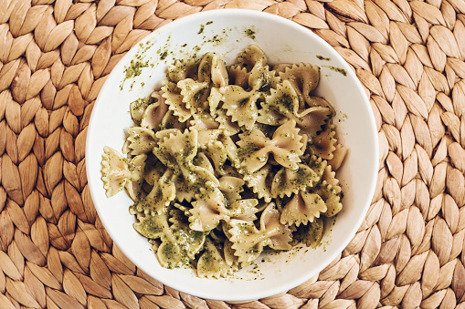 Bowl of pesto bow pasta on straw placemat