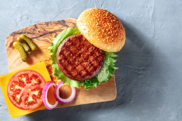 Hamburger ingredients, shot from above on a blue background Hamburger ingredients, shot from above on a blue background with a place for text. Sesame bread, meat patty, green salad and red onion, overhead shot spanish hamburger stock pictures, royalty-free photos & images