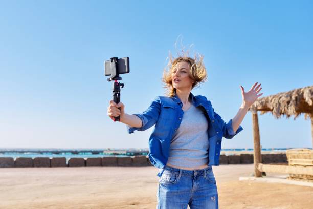istock Middle aged woman with smartphone looking at webcam talking recording video 1334426877