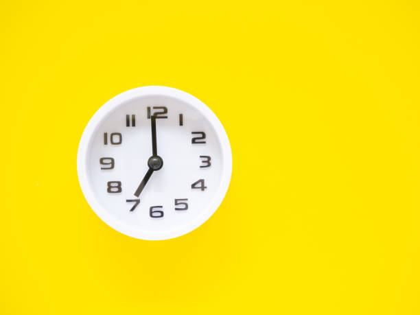 istock Top view, Flat lay, white clock show time at 7 o'clock on office yellow workplace tabletop. Copy space for your text. Business and education concept. 1334430096