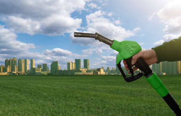 Hand with fuel nozzle with inscription BIO on the background of green eco city. stock photo