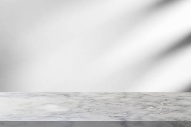 istock Marble table with window shadow drop on white wall background for mockup product display 1334432929