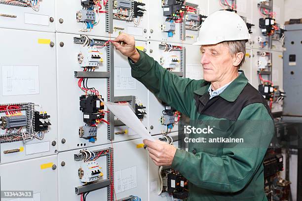 Senior Worker Standing Near Electrical Panel With An Electric Screwdriver Stock Photo - Download Image Now